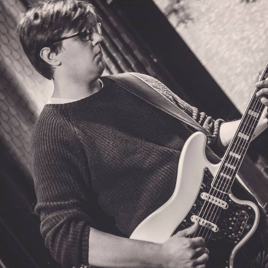 A photo of Harrison playing an electric guitar at a concert.